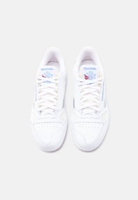 Ζευγάρι λευκά αθλητικά παπούτσια Reebok με μπλε και κόκκινα λογότυπα, δεμένα με κορδόνια και φωτογραφημένα από πάνω σε απλό λευκό φόντο.