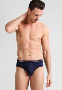 Marineblaue Baumwollslips mit einem weißen und roten Logo-Bund; zeichnen sich durch eine enge Passform und glatte Textur aus. Entwickelt für Komfort und Unterstützung.