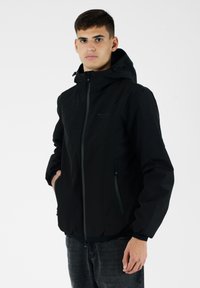 Giacca a cappuccio nera realizzata in materiale liscio e leggero. Caratterizzata da una zip frontale, polsini elasticizzati e tasche laterali con elementi di design eleganti.