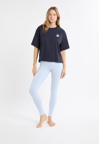 T-shirt en coton bleu marine oversize avec un logo sur le devant, associé à des leggings sans couture bleu clair, mettant en valeur une coupe ajustée et une texture lisse.