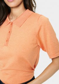 Pánská polokošile s krátkým rukávem v texturované světlé oranžové látce, s límečkem a zapínáním na tři knoflíky. Jednoduchý a přiléhavý střih.