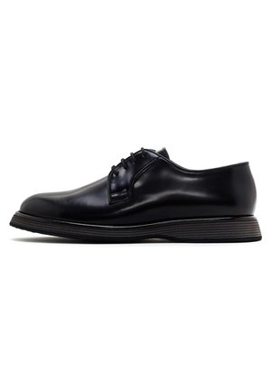 Zapato de vestir de cuero negro con un acabado suave, punta redondeada, diseño de cordones con cinco ojales y suela texturizada en contraste.