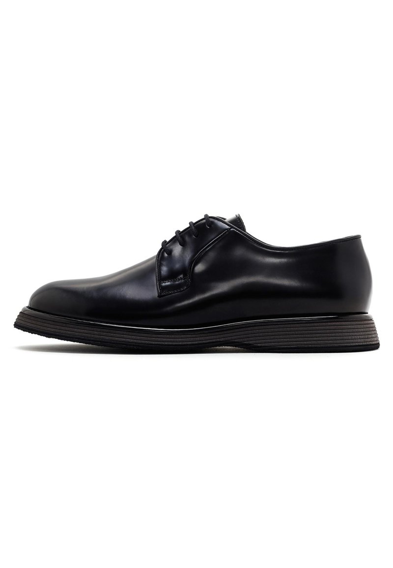 Chaussure habillée en cuir noir avec une finition lisse, bout arrondi, design à laçage à cinq œillets, et semelle texturée contrastante.