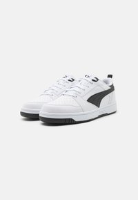 Hvite sneakers med overdel i glatt lær, svarte detaljer, perforert design, tradisjonelle snørebånd og tykk gummisåle.