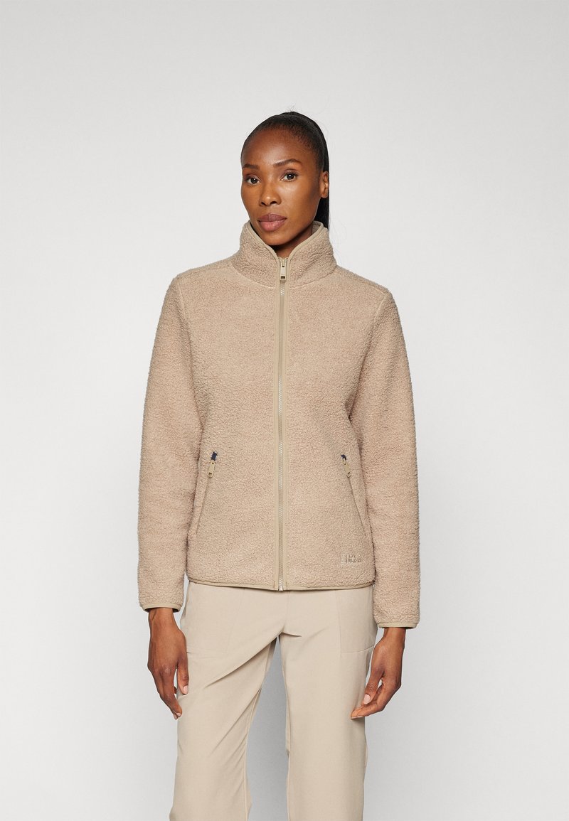 Giacca in pile beige con colletto alto e zip frontale; presenta due tasche laterali con tirazip a contrasto e un logo sull'orlo.
