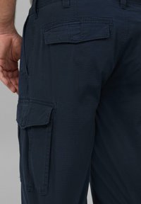 Navy cargo spodnie wykonane z lekkiego materiału. Posiadają wiele kieszeni, luźny krój i przeszycia.