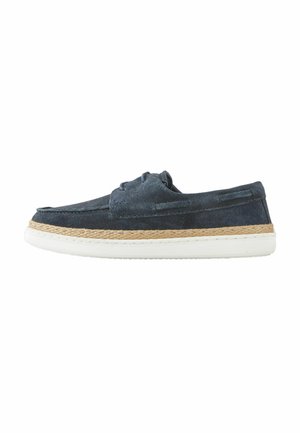 Navy blue suede boat shoe with woven jute midsole and elastic laces, featuring a streamlined shape and flat white rubber outsole.