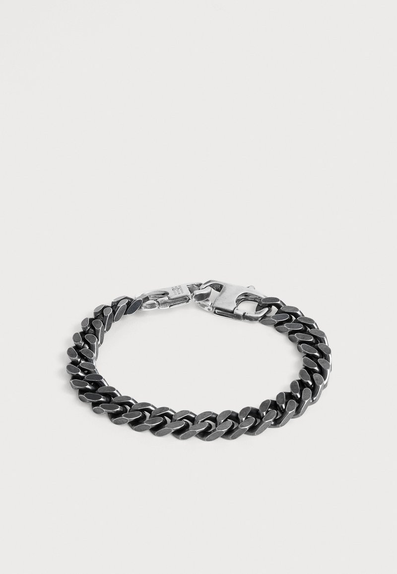 Pulsera de cadena gruesa de plata con eslabones planos e interconectados y cierre seguro de langosta sobre un fondo claro y liso.