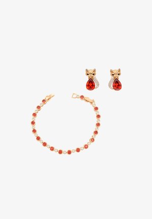 Złota bransoletka z naprzemiennie umieszczonymi czerwonymi i przezroczystymi kamieniami, zestawiona ze złotymi kolczykami w kształcie lisów z czerwonymi kamieniami w kształcie kropli i małymi przezroczystymi kryształkami.