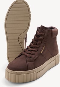 Baskets montantes en cuir marron avec une surface texturée, un col rembourré et une semelle plateforme de couleur crème avec un motif nervuré.