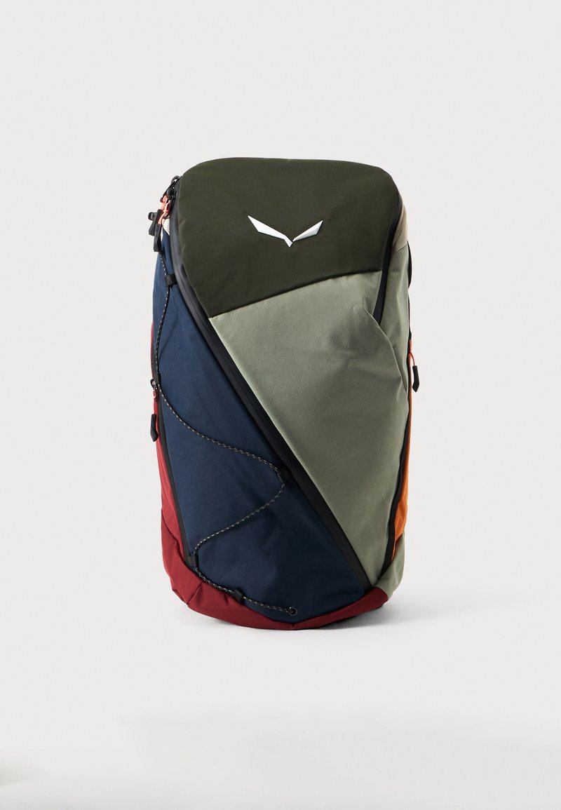 Sac à dos multicolore à motif triangulaire avec des sections vertes, bleu marine, rouges et orange et un logo abstrait blanc sur le dessus.