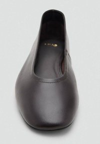 Zapato plano de cuero marrón oscuro con punta redondeada y escote bajo, visto desde arriba sobre un fondo gris claro.