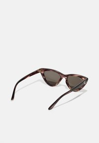 Brown tortoiseshell cat-eye sunglasses with dark lenses, smooth finish, and thin black arms featuring a small logo on the side.