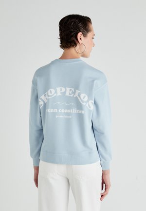 Light blue sweatshirt with a crew neckline and long sleeves. Back features white text reading "SKOPELOS ocean coastlines greece island."