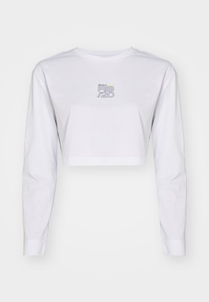 Camiseta cropped de manga larga blanca hecha de algodón. Presenta un logo impreso en azul y amarillo en el pecho. Diseño simple y limpio con mangas ajustadas.