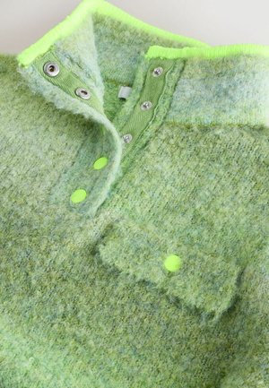 Zelený pulovr z vlněné směsi s texturovaným povrchem, neonově zelenými akcenty, druky a náprsní kapsou s jasně barevným detailem na knoflíku.