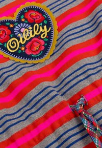 Grijze stof met rode, roze en marineblauwe strepen; bevat een hartvormig stukje met bloemenborduursel en gouden tekst, geaccentueerd door een kleurrijke strik.