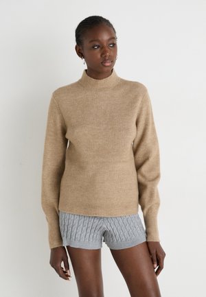 Tan geribbelde trui met een hoge hals en lange mouwen, gecombineerd met grijze textuur shorts. Zacht materiaal, aansluitend ontwerp en casual stijl.