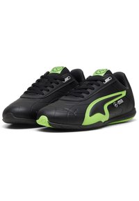 Baskets noires de sport avec une tige en cuir lisse, présentant des accents verts, des panneaux latéraux texturés et des lacets plats pour un ajustement sûr.