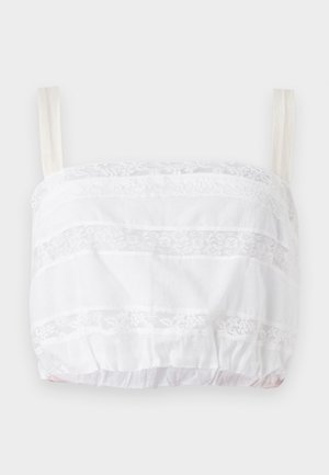 Hvit croppet topp med blonde detaljer, med horisontale striper av stoff og blonder, justerbare stropper og elastisk bunn.