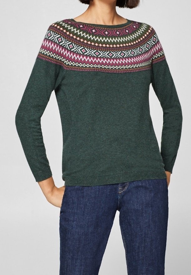 Maglione verde lavorato a maglia con giromanica rotondo e un motivo geometrico multicolore. Maniche lunghe e orlo aderente. Indossato con jeans blu.