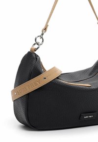 Sac à main noir texturé avec une sangle marron et des anneaux argentés, avec le logo "Suri Frey" sur la sangle et l'étiquette avant.
