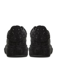 Paire de chaussures noires à enfiler vue de dos, ornées de petits clous noirs brillants avec une semelle épaisse et texturée.