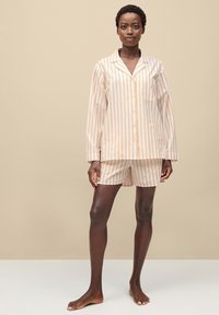 Gestreepte pyjama set met een knoopsluiting, lange mouwen en shorts. Kleuren zijn lichtperzik en wit. Gemaakt van zacht katoen.