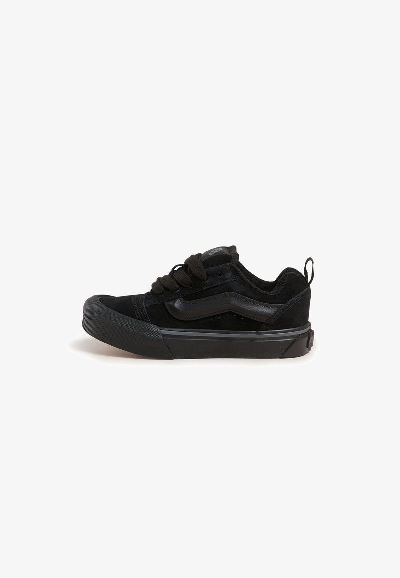Black sneakers with a suede upper, featuring a rubber toe cap, textured accents, and flat laces, designed for casual wear.