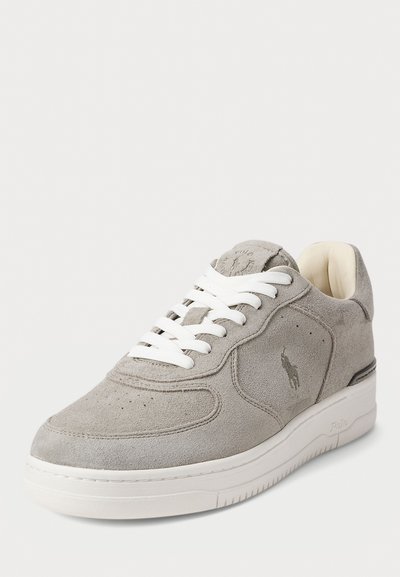 Sneaker grigio scamosciato con lacci bianchi, con perforazioni, un logo sul lato e una suola intermedia bianca imbottita. Fodera interna morbida.