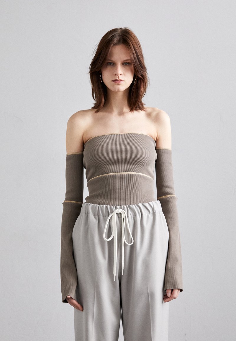 Brun ribbet strapless topp med ekstra lange ermer og lysegrå snøretruser. Myk tekstur og minimalistisk design.