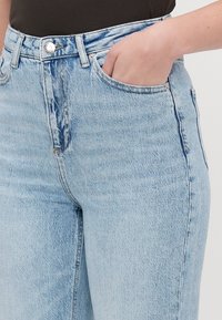 Ljusblå denimjeans med högmidjad design, något slitage och framfickor. Tyget har en mjuk textur och en urtvättad look.