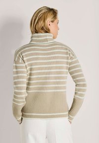 Beige gestreifter Rollkragenpullover mit weißen Streifen, ausgestattet mit Rippdetails am Kragen, an den Bündchen und am Saum. Weicher, strukturierter Strickstoff.