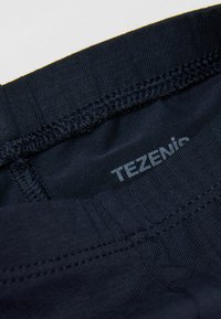 Tmavě modrý látkový pas s viditelným šitím a vytištěným názvem značky "TEZENIS" uvnitř v světle šedé barvě.