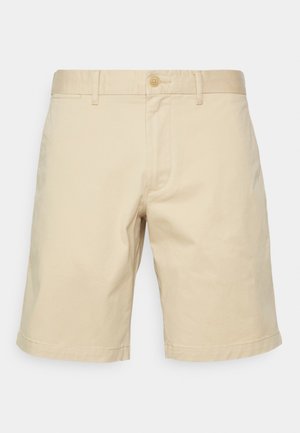 Shorts beiges pour homme, longueur genou, avec passants de ceinture, fermeture par bouton et design simple et épuré sur fond uni.