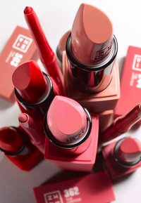 En samling av läppstift i olika röda och rosa nyanser, med bullet-, krita- och flytande former, i glänsande svart och matt förpackning.