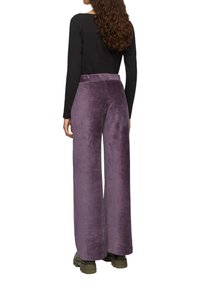 Wijde paarse fleece broek met een hoge tailleband, zachte textuur en zijnaad. Draag een zwart langemouwen top en groene laarzen.