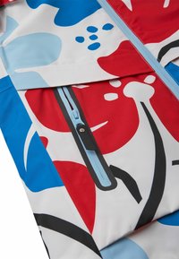 Wasserdichte Jacke mit einem lebhaften Blumenmuster in Rot, Blau und Weiß, mit einer Reißverschlusstasche in Hellblau und schwarzen Akzenten.