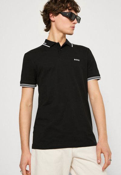 Polo noir avec un col blanc et des rayures sur les manches, doté d'une patte de boutonnage à trois boutons et d'un logo sur le devant. Fabriqué en tissu de coton lisse.