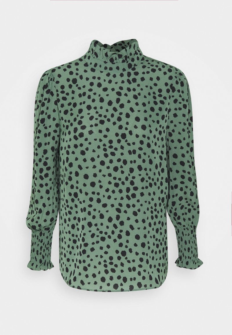 Blouse verte à manches longues avec pois noirs irréguliers, col montant à volants et poignets à volants smockés.