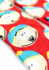 Calzini con personaggi dei cartoni animati caratterizzati da uno sfondo rosso con facce ripetute di un personaggio, cappello blu e accenti gialli. Morbido tessuto a maglia.