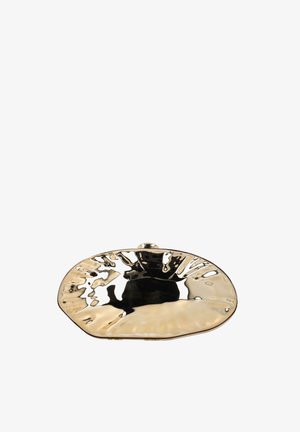 Kultainen metallinen clutch-laukku, kiiltävällä epäsäännöllisellä vasaratulla pinnalla ja pyöristetyn ovaalilla muodolla valkoista taustaa vasten.