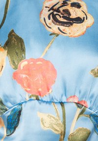 Tessuto a fantasia floreale blu, con rose rosa e arancioni e foglie verdi, caratterizzato da una superficie liscia e setosa e dettagli di cucitura arricciata.