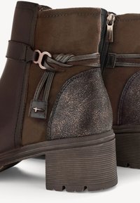 Bottines marron à talons blocs empilés, fermeture éclair latérale, nœud décoratif en cuir et contreforts de talon à texture métallique.