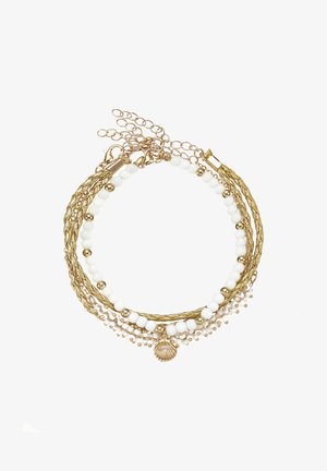 Multi-strand necklace featuring white beads, gold accents, and woven cords. Includes a small shell charm as a notable detail.