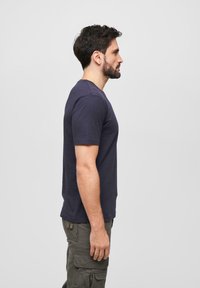 Námořnická modrá bavlněná tričko s krátkými rukávy, kulatým výstřihem a volným střihem, spárované s olivově zelenými cargo kalhotami.