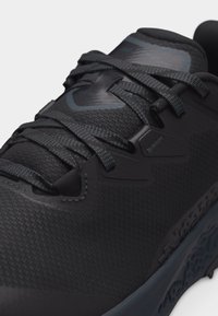 Μαύρο αθλητικό παπούτσι με υφασμάτινη υφή, κορδόνια με σχέδιο και μαλακή σόλα, σχεδιασμένο για τρέξιμο ή προπονήσεις.