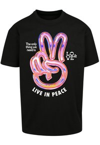Sort bomulds t-shirt med et farverigt fredssymbolgrafik og fed tekst, der lyder: "Det eneste vi har brug for er KÆRLIGHED & AT LEVE I FRED."