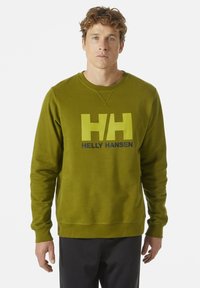 Olivově zelená mikina s kulatým výstřihem, která má velké žluté logo "HH" a text "HELly HANSEN" přes hrudník. Měkká textura.