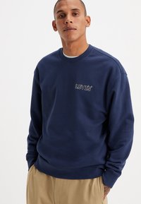 Felpa Levi's blu navy con collo a girocollo, polsini a coste e un piccolo logo ricamato sul petto. Tessuto di texture liscia.